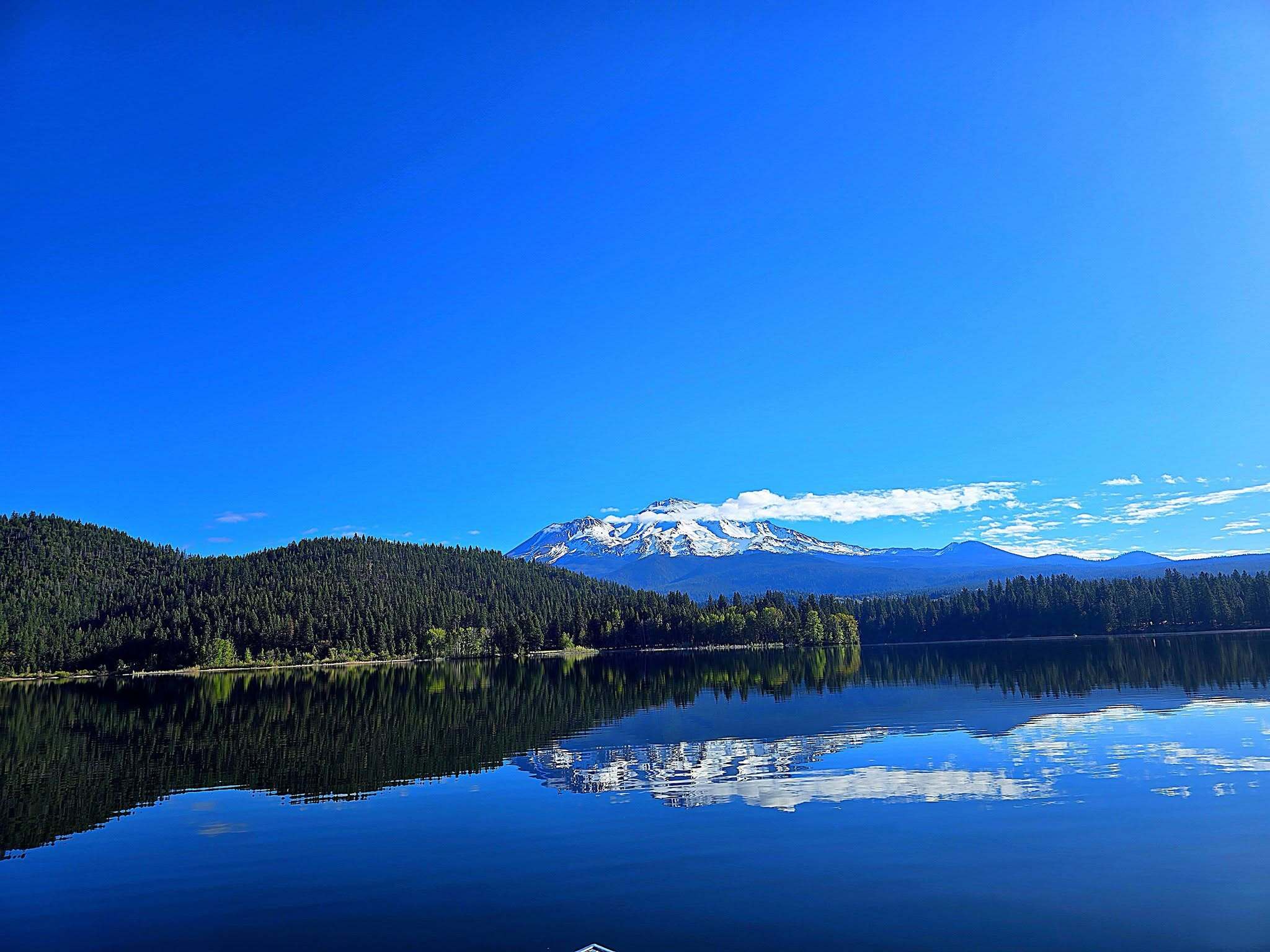 Snow-capped Mount Shasta reflected in the still water of a Northern California lake